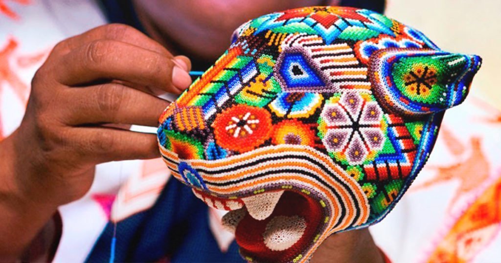 Ojo de Venado: Tradición y protección 3 Artesana realizando arte huichol con una figura de un jaguar hecha de chaquira